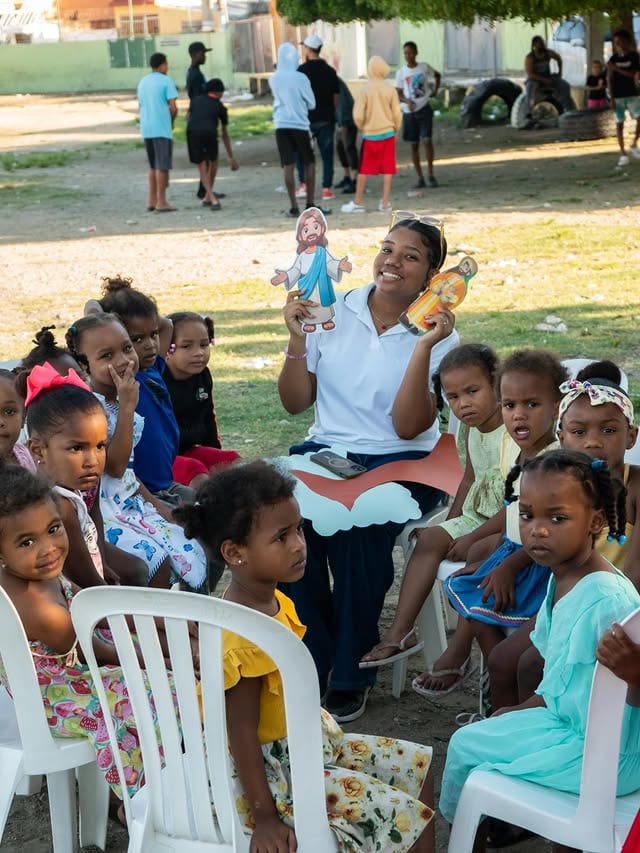 Voluntaria con niños y figuras de Jesús